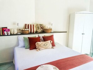 Ein Hotelzimmer mit Bett, Kissen, einem Regal mit Dekoration und einem Kleiderschrank.
