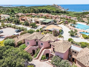 Ein Küsten-Villa-Komplex mit mehreren Gebäuden, einem Schwimmbad und einem angelegten Garten.