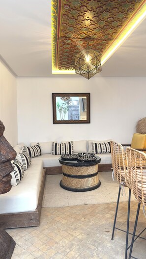 A living room with a sofa, a round coffee table, and a wicker chair. - Fabulous 2-bedroom riad with AC in vibrant Marrakesh (Marrakesh)