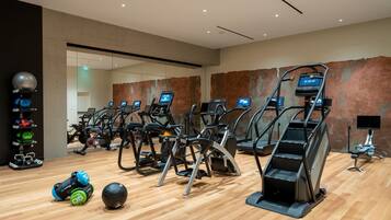 Un gimnasio moderno con varias cintas de correr, equipo de levantamiento de pesas y suelo de madera.