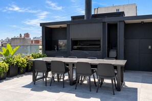 Een eethoek buiten met een ingebouwde barbecue en zitplaatsen.
