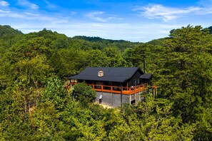Una cabana amb un balcó, envoltada per un bosc dens.