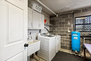 Una sala de bugaderia amb rentadora, assecadora i un dipòsit blau d'aigua.