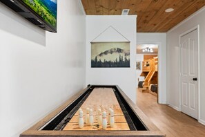 Una taula de futbolí a una habitació amb parets blanques, un sostre de fusta i un quadre d'un paisatge de muntanya.