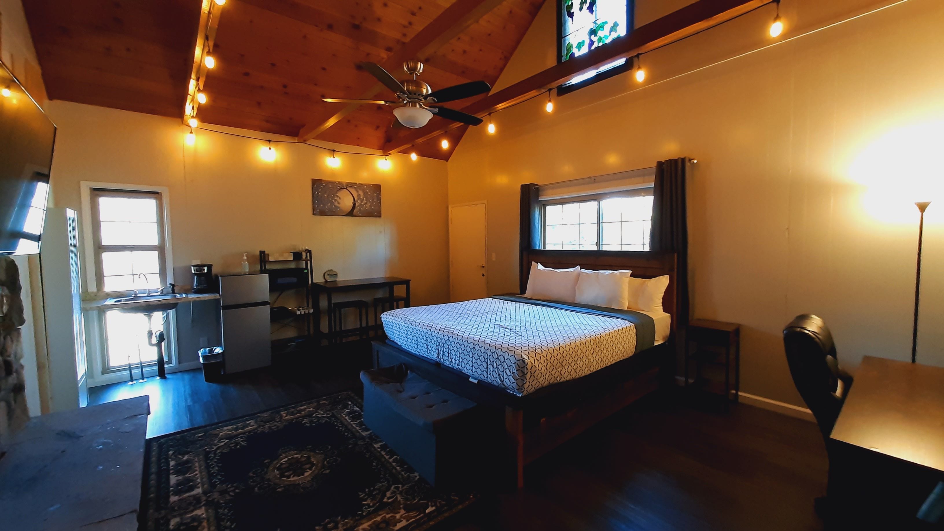 A bedroom with a bed, desk, chair, and a ceiling fan.
