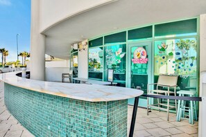 Ein moderner Außenbereich mit einer geschwungenen Marmor-Theke und Glaswänden, mit einem Schild für 'Piper's Place Frozen Treats'.