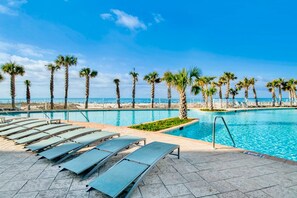 A swimming pool with lounge chairs and palm trees, surrounded by a beach and clear sky. - Turquoise Place C2104 | Special Stocked Extras! | Sleeps 12 (Orange Beach)