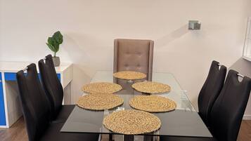 A modern dining area with a glass table, black upholstered chairs, and woven placemats.