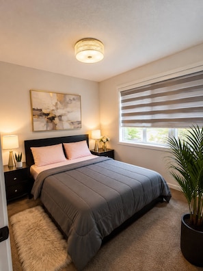 A bedroom with a bed, bedside tables, lamps, a painting, a window with blinds, and a potted plant. - Spaciouscalgaryhome l 4 Bedrooms l Sleeps 8 Plus (Calgary)