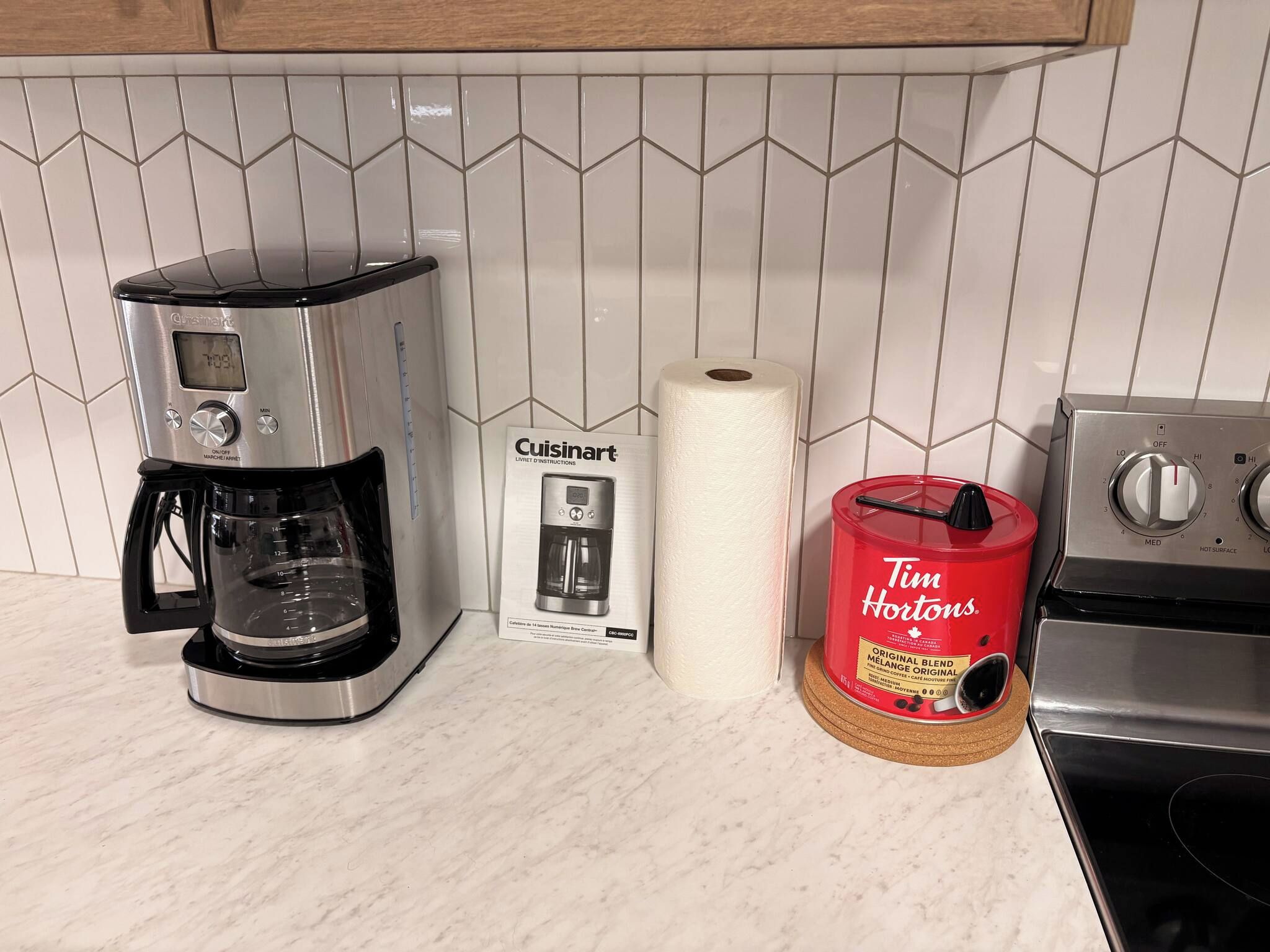 Una cucina con una macchina da caffè, un dispenser per cialde di caffè e un rotolo di carta assorbente.
