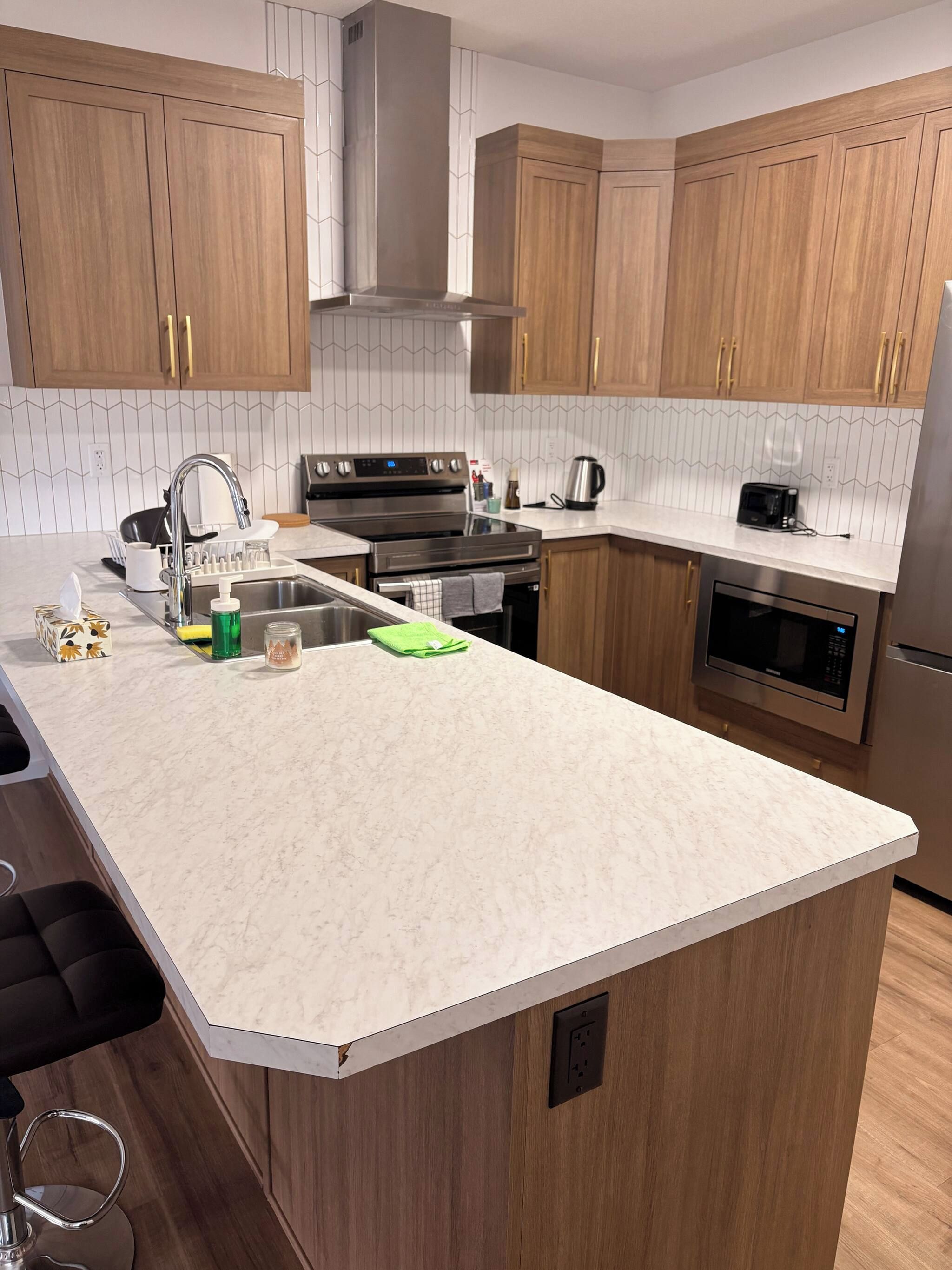 A modern kitchen with wooden cabinets, a stainless steel range, and a large island with a sink.