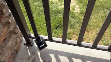 A security lock attached to a metal gate, with a concrete floor and a grassy area in the background.
