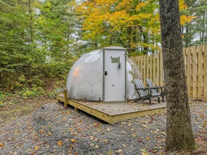 A geodesic dome structure with a door, a small deck, and two chairs. - Aries | Black Lake Glamping Dome (Hammond)