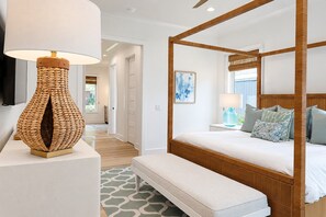 Un lit à baldaquin avec une tête de lit en bois, une lampe de sol en osier et un tapis à motifs.