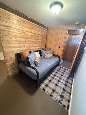 Une pièce avec un lit, des murs lambrés en bois, un tapis à motifs et une porte.