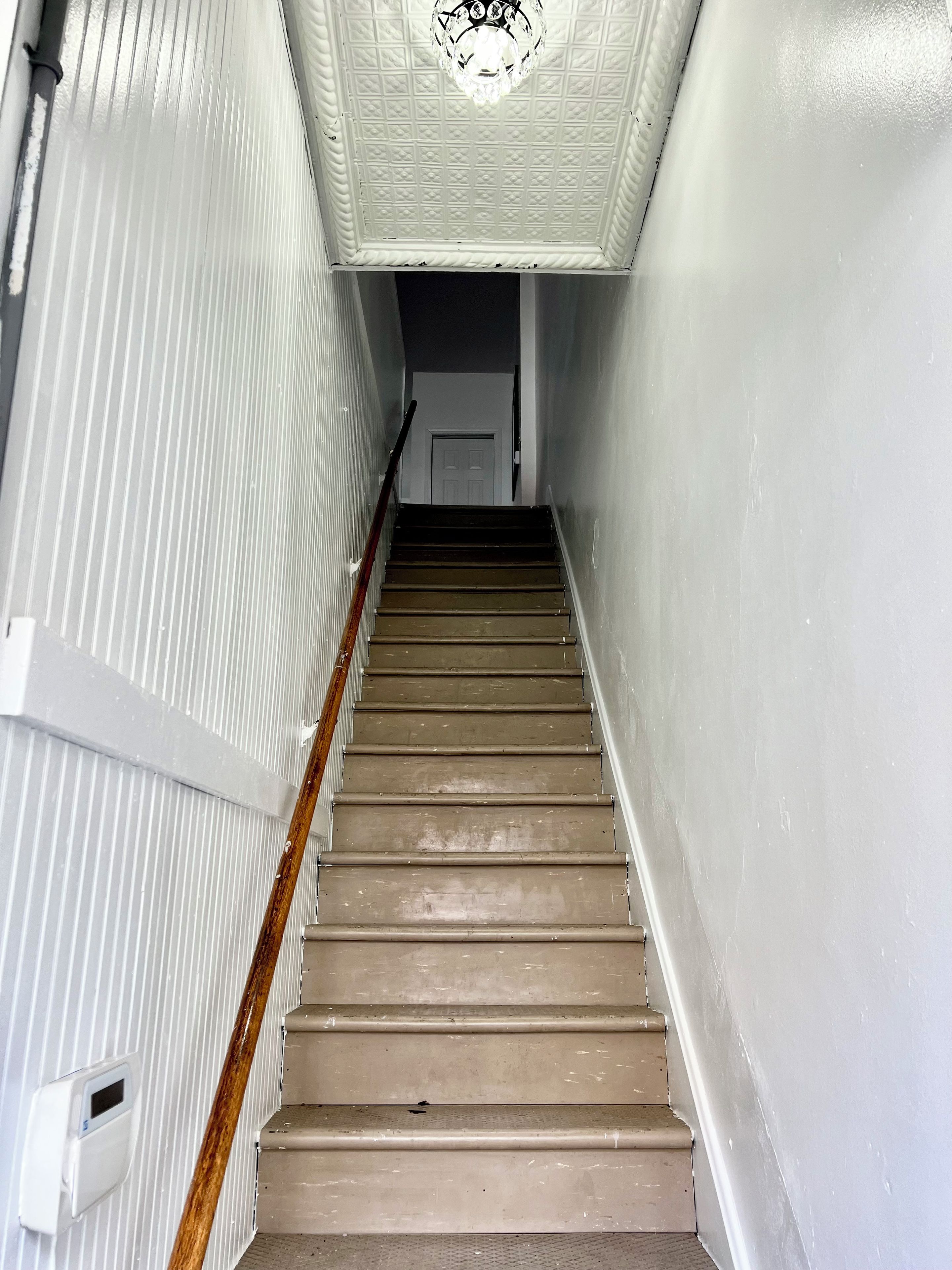 A staircase with a handrail, a door at the top, and a textured ceiling.