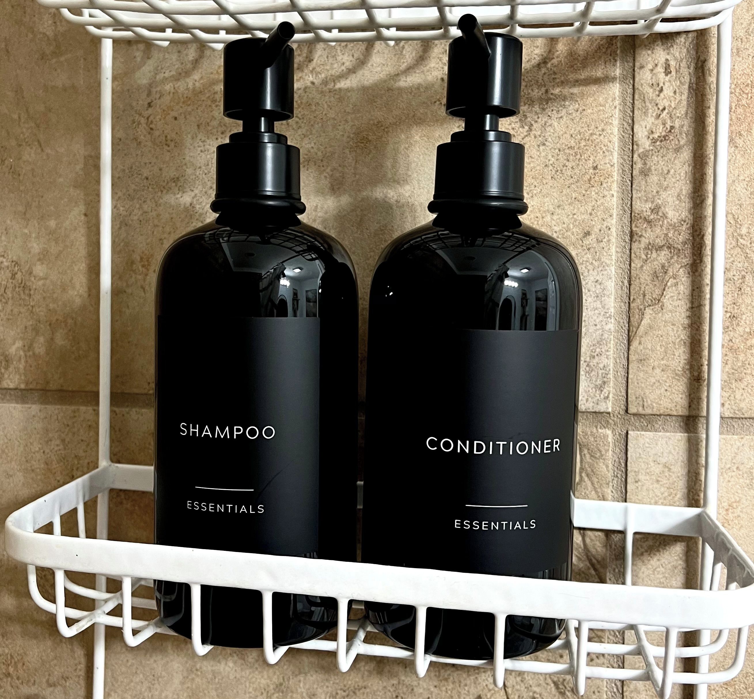 Duas garrafas pretas de shampoo e condicionador sobre uma prateleira branca.