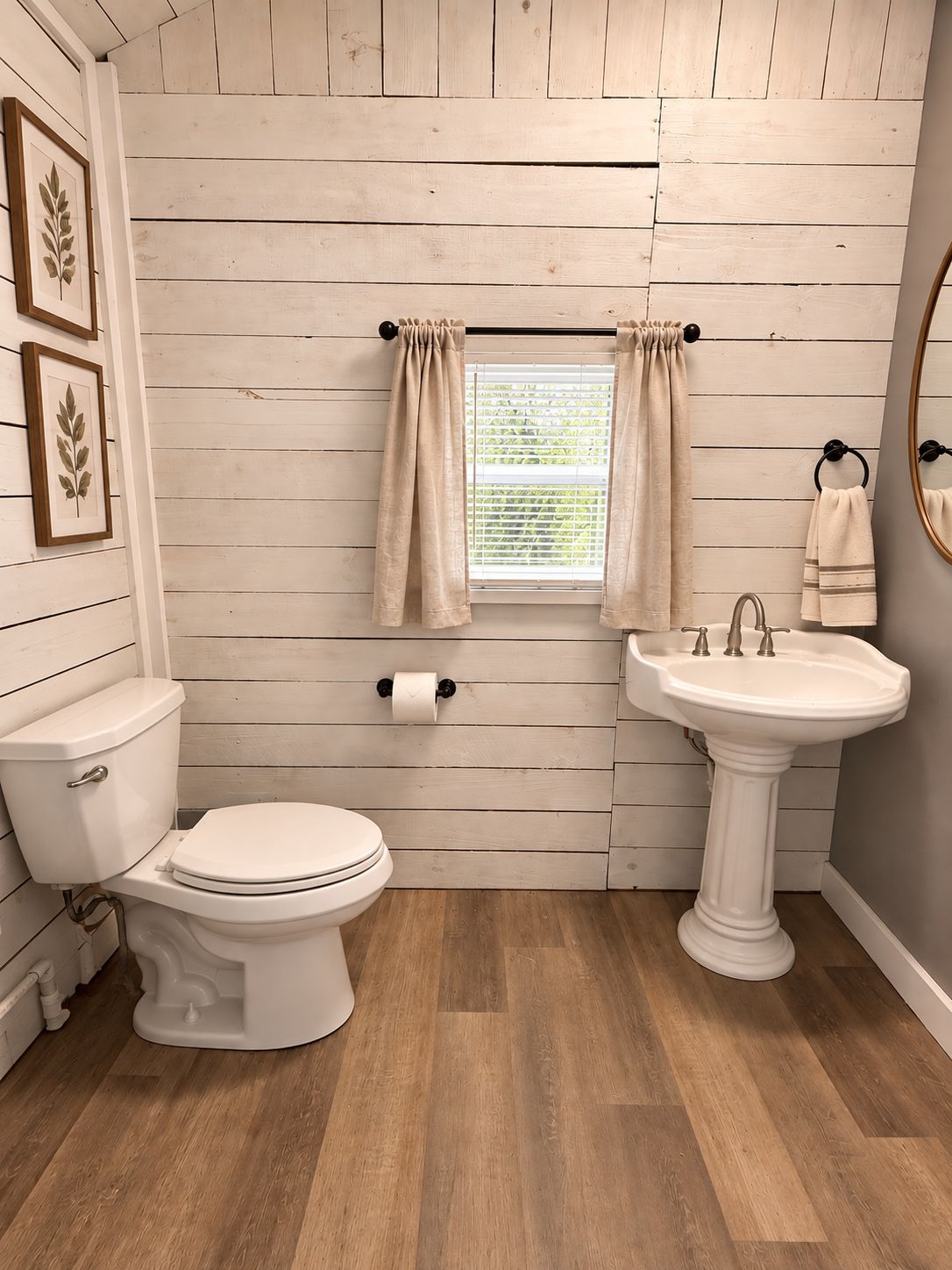 A bathroom with a toilet, sink, and window with curtains.