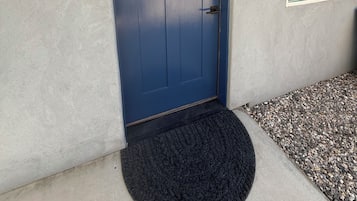 A blue door with a welcome sign, a window with a view, and a black doormat.