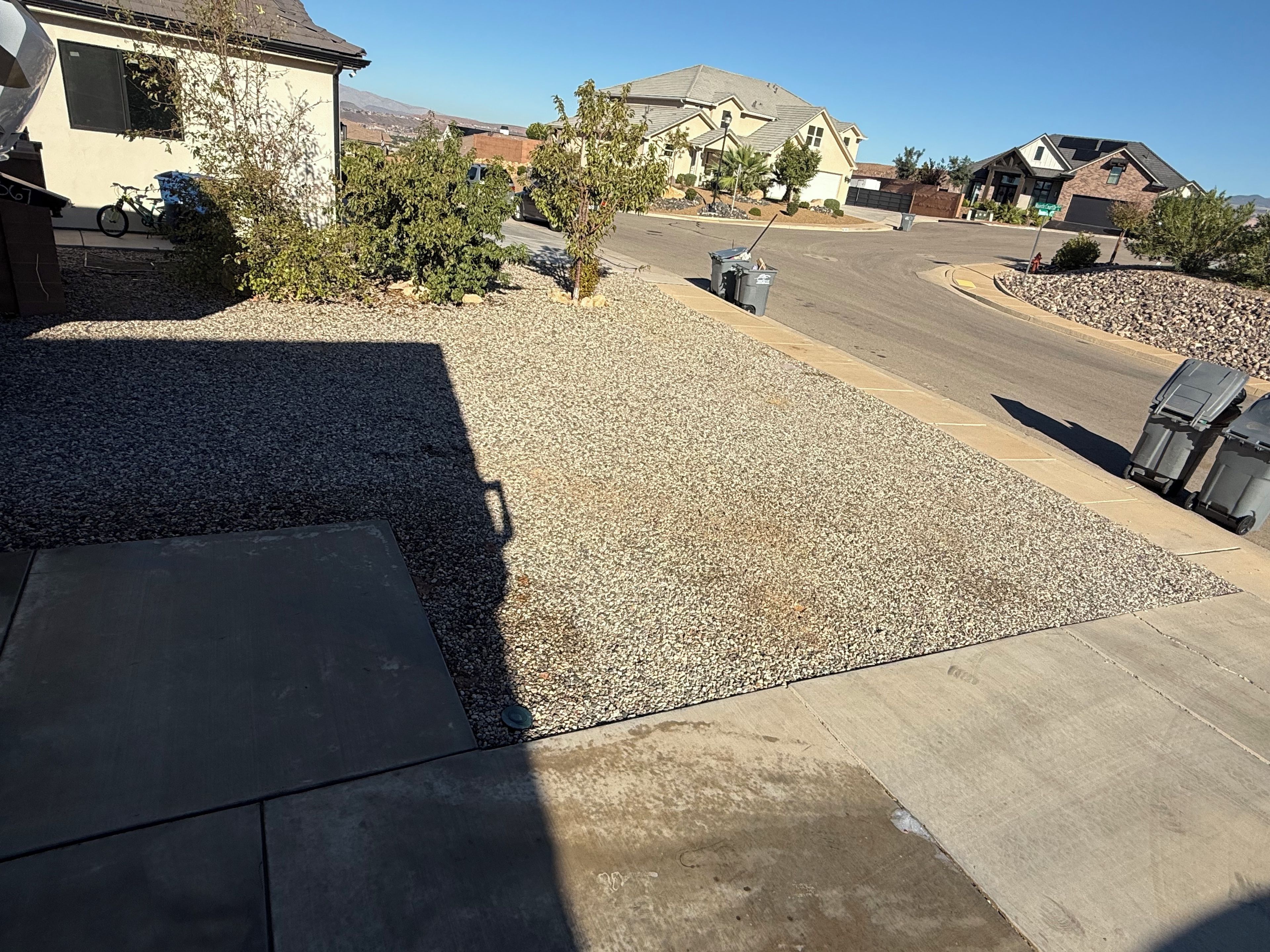 A residential driveway with a gravel area, a concrete path, and a parked bicycle.