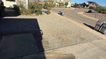 A residential driveway with a gravel area, a concrete path, and a parked bicycle.
