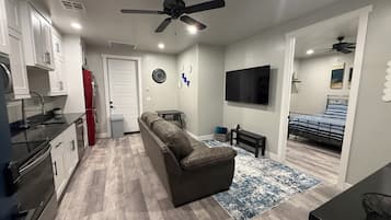 A compact living space with a kitchenette, a sofa, a TV, and a bed.