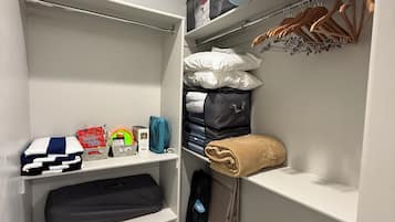 A closet with shelves, hanging space, and a folded blanket.