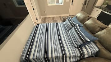 A bedroom with a bed, a sofa, and a small kitchenette.