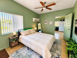 A bedroom with a bed, bedside table, lamp, and a ceiling fan. - The Fremont Studio - 2min from Fremont St! (Las Vegas)