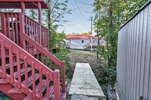 Eine Holztreppe führt zu einem Haus mit rotem Dach, umgeben von Grün.