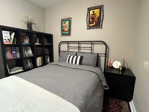 A bedroom with a bed, a bookshelf, and two framed pictures on the wall. - 2-bedroom apartment in beautiful Northbrook with AC and comfort (Northbrook)