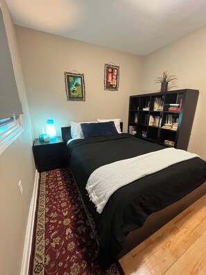 A bedroom with a bed, bedside tables, a bookshelf, and a patterned rug.