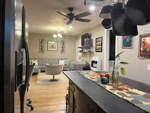 Una cocina moderna con una isla central, un ventilador de techo y un comedor con un sofá y una mesa de centro.