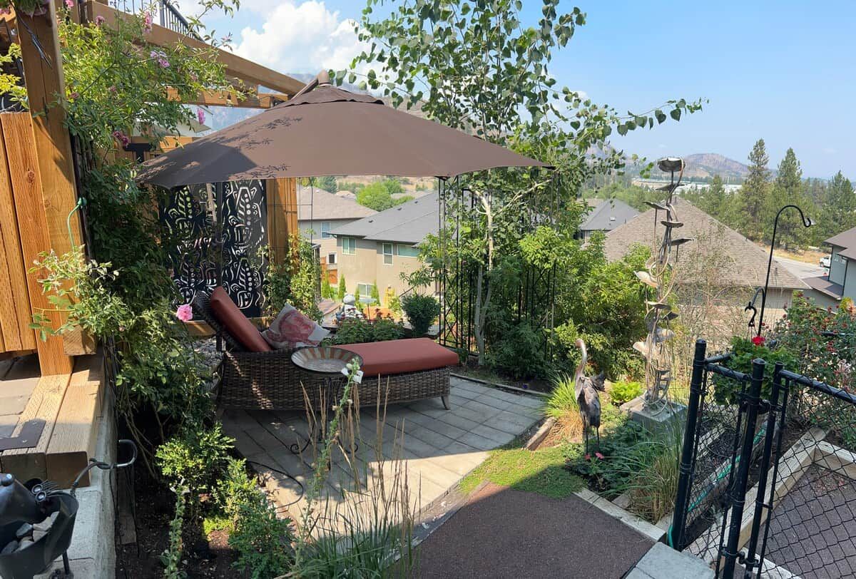 An outdoor patio with a wicker sofa, a table, and a large umbrella.