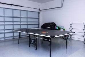 A ping pong table in a garage with a bicycle and a sports bag. - Prime Location Near Parks at Bella Vida Resort (Kissimmee)