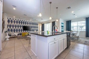 A modern kitchen with a central island, white cabinetry, and a flat-screen TV mounted on the wall. - Prime Location Near Parks at Bella Vida Resort (Kissimmee)