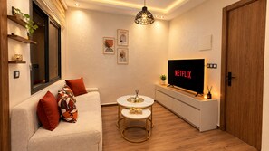 Ein Wohnzimmer mit einer Couch, einem Couchtisch, einem Fernseher und einer Holztür.