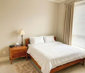 A bedroom with a single bed, a nightstand, a lamp, and a window with curtains. - Luxury Richmond Home (Richmond)