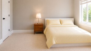A bedroom with a bed, nightstand, lamp, and a window with natural light. - Luxury Richmond Home (Richmond)
