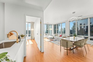 A modern apartment with a kitchen, dining area, and large windows offering city views. - Cozy & Chic Downtown Oasis (Vancouver)