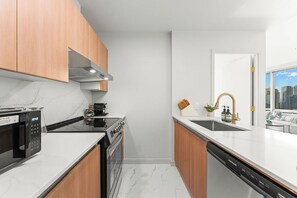 A modern kitchen with a microwave, stove, oven, and dishwasher. - Cozy & Chic Downtown Oasis (Vancouver)