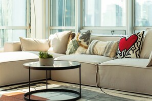A modern living room with a beige sofa, a round black coffee table, and a potted plant. - Cozy & Chic Downtown Oasis (Vancouver)