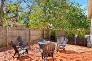 An outdoor patio with a brick floor, surrounded by a wooden fence and trees. - Grand Rhapsody  4Bed 2Bath  Huge Yard! (Abilene)