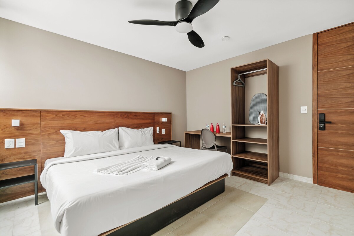 Quarto de hotel com cama, guarda-roupa, espelho e ventoinha no teto.