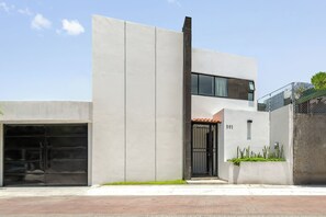 A modern two-story building with a garage, a balcony, and a small garden area. - Calesa By Homirent  (Santiago de Querétaro)