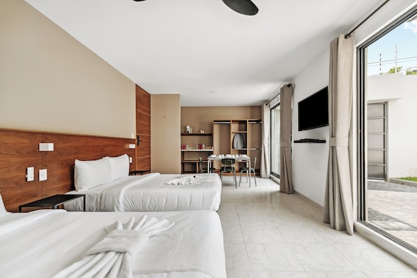 A hotel room with two beds, a dining area, and a TV.