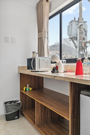 A kitchen with a microwave, kettle, and a red cup on the counter. - Calesa By Homirent  (Santiago de Querétaro)