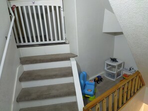 A staircase with a wooden handrail, a white railing, and a landing area with toys and a small white shelf. - Charming Sanger Home - King Bed & Loft - Sleeps 6 (Sanger)