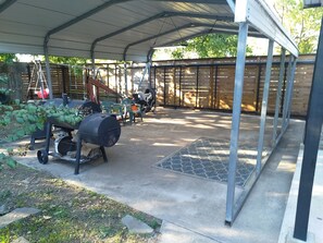 A covered outdoor area with a barbecue grill, a ladder, and a stroller. - Charming Sanger Home - King Bed & Loft - Sleeps 6 (Sanger)