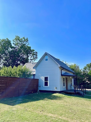 A single-story house with a gabled roof, a front porch, and a wooden fence. - Charming Sanger Home - King Bed & Loft - Sleeps 6 (Sanger)
